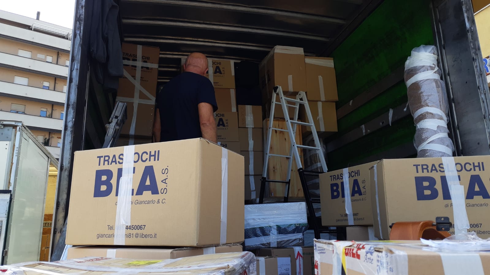 Foto da dietro di un camion per il trasloco aperto con dentro i pacchi